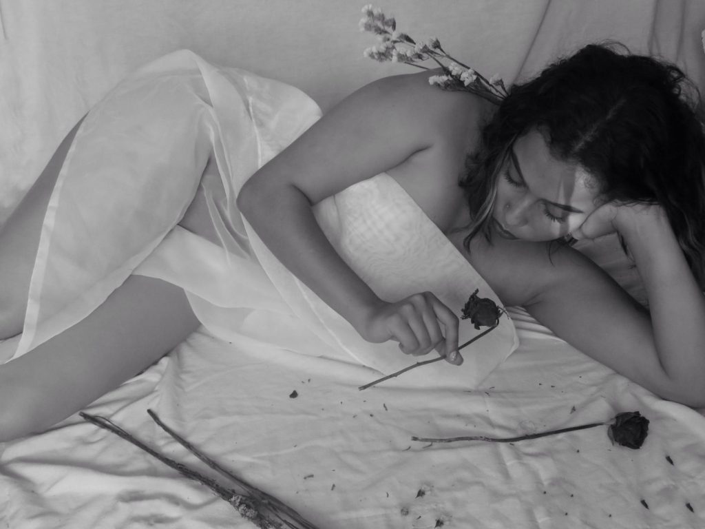 femme allongé un tissu fin sur elle tenant une rose